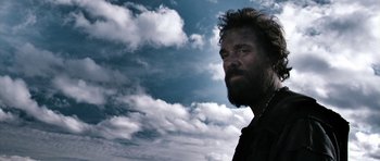 Movie still from “Valhalla Rising” (2009), directed by Nicolas Winding Refn – A man with a long beard is standing in front of a cloudy sky; Close Up shot, Low angle