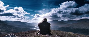 Movie still from “Valhalla Rising” (2009), directed by Nicolas Winding Refn – A man sitting on top of a grass covered hill; Wide shot, Low angle