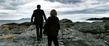 Movie still from “Valhalla Rising” (2009), directed by Nicolas Winding Refn – A man and a woman are walking on a rocky path; Wide shot, High angle