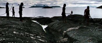Movie still from “Valhalla Rising” (2009), directed by Nicolas Winding Refn – A person standing on a rock near a body of water; Extreme Wide shot, High angle