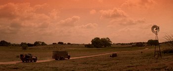 Movie still from “Vampires” (1998), directed by John Carpenter – A truck is driving down a dirt road near a field; Extreme Wide shot, Low angle