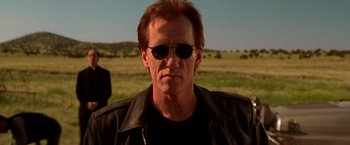 Movie still from “Vampires” (1998), directed by John Carpenter – A person wearing sunglasses and a leather jacket; Close Up shot, Low angle