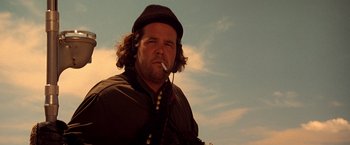 Movie still from “Vampires” (1998), directed by John Carpenter – A man with a beard and a hat smoking a cigarette; Close Up shot, Low angle