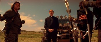 Movie still from “Vampires” (1998), directed by John Carpenter – A man standing in front of a tractor in a field; Wide shot, Low angle
