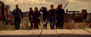 Movie still from “Vampires” (1998), directed by John Carpenter – A group of people walking across a grass field; Wide shot, Low angle
