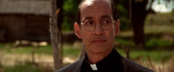 Movie still from “Vampires” (1998), directed by John Carpenter – A man wearing glasses and a priest's outfit; Close Up shot, Low angle