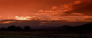 Movie still from “Vampires” (1998), directed by John Carpenter – The sun sets over a field of grass and trees; Extreme Wide shot, Low angle