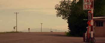 Movie still from “Vampires” (1998), directed by John Carpenter – A car driving down a road near a tree; Extreme Wide shot, Low angle