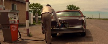 Movie still from “Vampires” (1998), directed by John Carpenter – A man pumping gas into the trunk of a car; Wide shot, Low angle