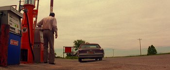 Movie still from “Vampires” (1998), directed by John Carpenter – A man standing next to a car on the side of the road; Wide shot, Low angle