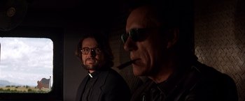 Movie still from “Vampires” (1998), directed by John Carpenter – A man smoking a cigarette next to another man wearing sunglasses; Close Up shot, Low angle