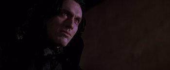 Movie still from “Vampires” (1998), directed by John Carpenter – A person wearing a suit and tie; Close Up shot, Low angle