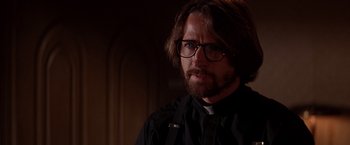 Movie still from “Vampires” (1998), directed by John Carpenter – A man with a beard wearing glasses and a priest's outfit; Close Up shot, Low angle