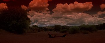 Movie still from “Vampires” (1998), directed by John Carpenter – A person laying on the ground under a cloudy sky; Extreme Wide shot, Low angle