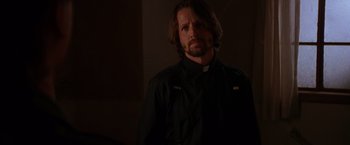 Movie still from “Vampires” (1998), directed by John Carpenter – A man with long hair wearing a priest's outfit; Close Up shot, Over the shoulder angle