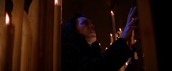 Movie still from “Vampires” (1998), directed by John Carpenter – A man holding a lit candle in a dark room; Medium shot, Low angle