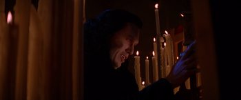 Movie still from “Vampires” (1998), directed by John Carpenter – A man sitting in front of a group of lit candles; Medium shot, Low angle