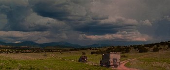 Movie still from “Vampires” (1998), directed by John Carpenter – A truck driving down a road under a cloudy sky; Extreme Wide shot, Low angle