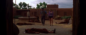 Movie still from “Vampires” (1998), directed by John Carpenter – A man and a woman walking in front of dead bodies; Wide shot, Low angle