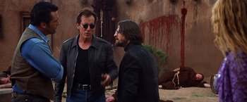 Movie still from “Vampires” (1998), directed by John Carpenter – Two men talking to each other in front of a building; Medium shot, Over the shoulder angle