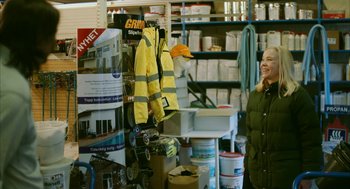 Movie still from “Violent” (2014), directed by Andrew Huculiak – A woman standing in a room filled with construction supplies; Medium shot, Over the shoulder angle