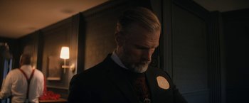 Movie still from “Violent Night” (2022), directed by Tommy Wirkola – A man in a suit with a badge on his lapel; Close Up shot, Low angle