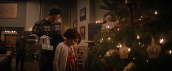 Movie still from “Violent Night” (2022), directed by Tommy Wirkola – A woman and a child standing next to a christmas tree; Medium shot, Over the shoulder angle
