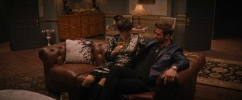 Movie still from “Violent Night” (2022), directed by Tommy Wirkola – A man and a woman sitting on a couch drinking a glass of wine; Medium shot, High angle