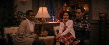 Movie still from “Violent Night” (2022), directed by Tommy Wirkola – A group of people sitting around a living room; Medium shot, Over the shoulder angle