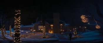 Movie still from “Violent Night” (2022), directed by Tommy Wirkola – A person walking in front of a building at night; Extreme Wide shot, Low angle