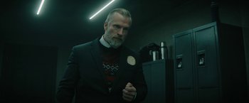 Movie still from “Violent Night” (2022), directed by Tommy Wirkola – A man in a suit standing in front of a bathroom mirror; Medium shot, Low angle