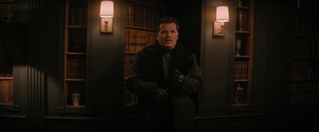 Movie still from “Violent Night” (2022), directed by Tommy Wirkola – A man in a coat and gloves in a room; Medium shot, Low angle