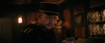 Movie still from “Violent Night” (2022), directed by Tommy Wirkola – A man wearing a black hat and a black jacket; Close Up shot, Low angle