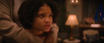 Movie still from “Violent Night” (2022), directed by Tommy Wirkola – A young girl is sitting in front of a lamp; Close Up shot, Over the shoulder angle