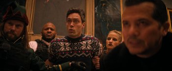 Movie still from “Violent Night” (2022), directed by Tommy Wirkola – A group of people standing in a room; Medium shot, Low angle