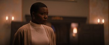 Movie still from “Violent Night” (2022), directed by Tommy Wirkola – A black woman with short hair wearing a white shirt; Medium shot, Low angle
