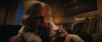Movie still from “Violent Night” (2022), directed by Tommy Wirkola – A man with long hair and a beard is smoking a cigarette; Close Up shot, Low angle