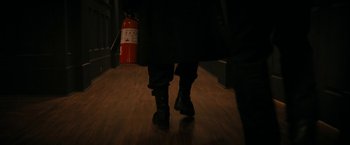 Movie still from “Violent Night” (2022), directed by Tommy Wirkola – A person walking on a hard wood floor next to a fire extinguisher; Extreme Close Up shot, High angle