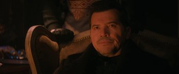 Movie still from “Violent Night” (2022), directed by Tommy Wirkola – A person sitting in a chair looking at the camera; Close Up shot, Over the shoulder angle