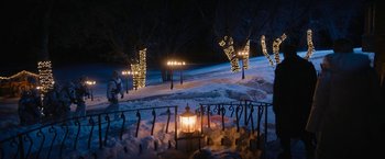 Movie still from “Violent Night” (2022), directed by Tommy Wirkola – A person walking in the snow at night with lights on; Extreme Wide shot, High angle