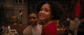 Movie still from “Violent Night” (2022), directed by Tommy Wirkola – Two young people smiling for the camera in front of a fire place; Close Up shot, Over the shoulder angle