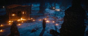 Movie still from “Violent Night” (2022), directed by Tommy Wirkola – A person standing in the snow near a fire pit; Extreme Wide shot, High angle