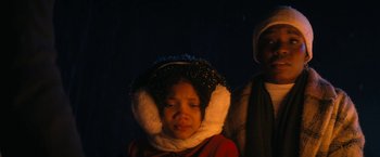 Movie still from “Violent Night” (2022), directed by Tommy Wirkola – A young girl wearing a fur collar and a red jacket; Close Up shot, Low angle