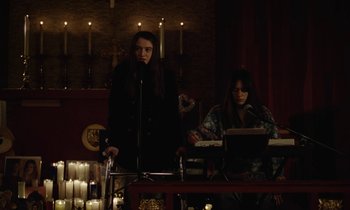 Movie still from “Vox Lux” (2018), directed by Brady Corbet – Two women are standing in front of a microphone; Medium shot, High angle