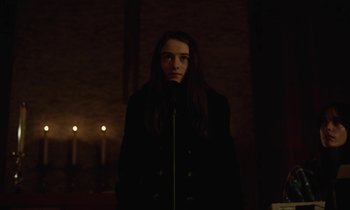 Movie still from “Vox Lux” (2018), directed by Brady Corbet – A woman standing in a dark room with candles in the background; Medium shot, Low angle