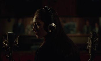 Movie still from “Vox Lux” (2018), directed by Brady Corbet – A woman wearing headphones in a dark room; Close Up shot, Over the shoulder angle