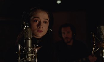Movie still from “Vox Lux” (2018), directed by Brady Corbet – A young girl with headphones on in a recording studio; Close Up shot, Over the shoulder angle