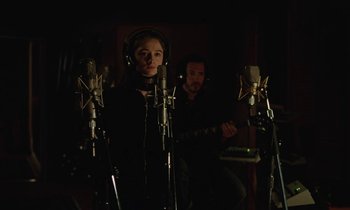 Movie still from “Vox Lux” (2018), directed by Brady Corbet – A woman in a recording studio with a microphone; Medium shot, Low angle