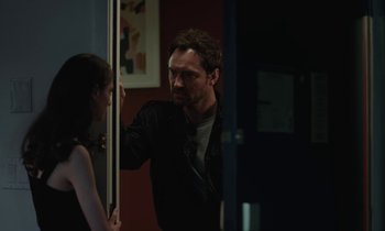 Movie still from “Vox Lux” (2018), directed by Brady Corbet – A man and a woman standing next to each other in a room; Medium shot, Over the shoulder angle