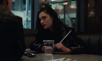 Movie still from “Vox Lux” (2018), directed by Brady Corbet – A woman sitting at a table with a glass of water; Close Up shot, Over the shoulder angle